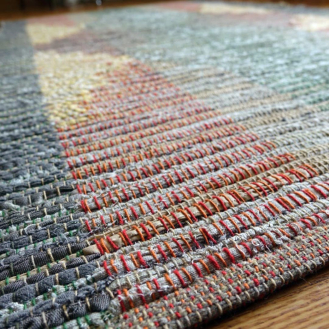 Custom rag rug. Symmetrical design in oranges, grays and yellows.