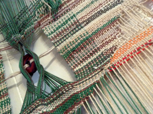 Detail of woven wall hanging by fiber artist Petra Guenthner Johnson. Close up of central weaving in brown and greens.