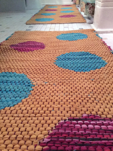 Close up of rag rugs woven by fiber artist Petra Guenthner Johnson. Bathroom with two rag rugs. Rag rugs are yellow with light blue and magenta polka dots alternating.