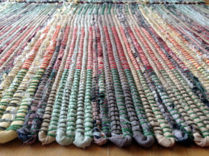 Detail of rag rug woven by fiber artist Petra Guenthner Johnson. Image shows selvage of small rag rug woven in soft yellow, green, and grays. Approximate size 18x27".