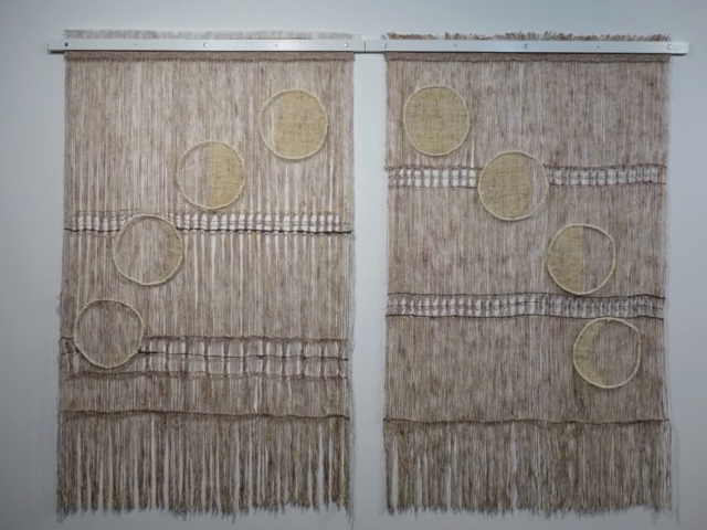 Woven artwork by fiber artist Petra Guenthner Johnson. Image of two open woven pink and gray panels with images of moon phases, woven in off-white, moving in a half circle across them. Each panel is 32x45"