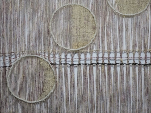 Detail of woven artwork by fiber artist Petra Guenthner Johnson. Image of open woven pink and gray panel with images of waxing moon phases, woven in off-white.