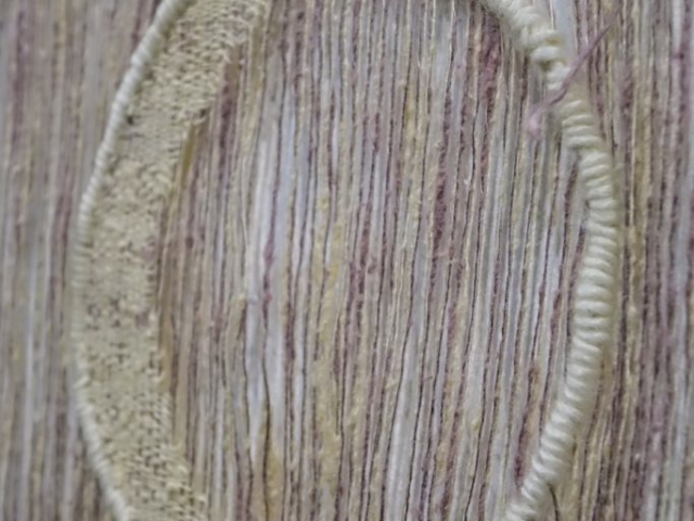 Detail of woven artwork by fiber artist Petra Guenthner Johnson. Detail of open woven pink and gray panel with image waning cresent moon, woven in off-white.